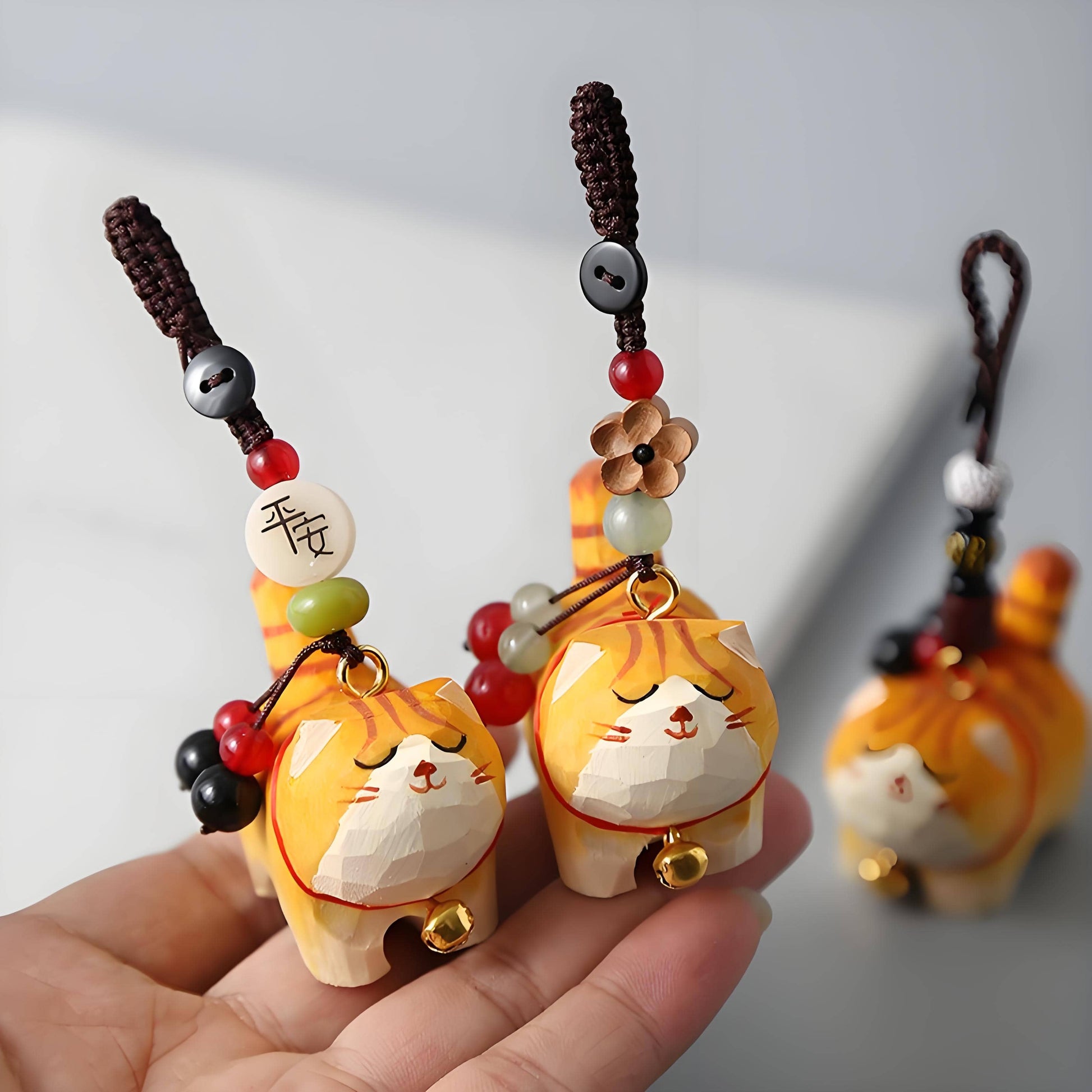3 orange cat charms on a hand